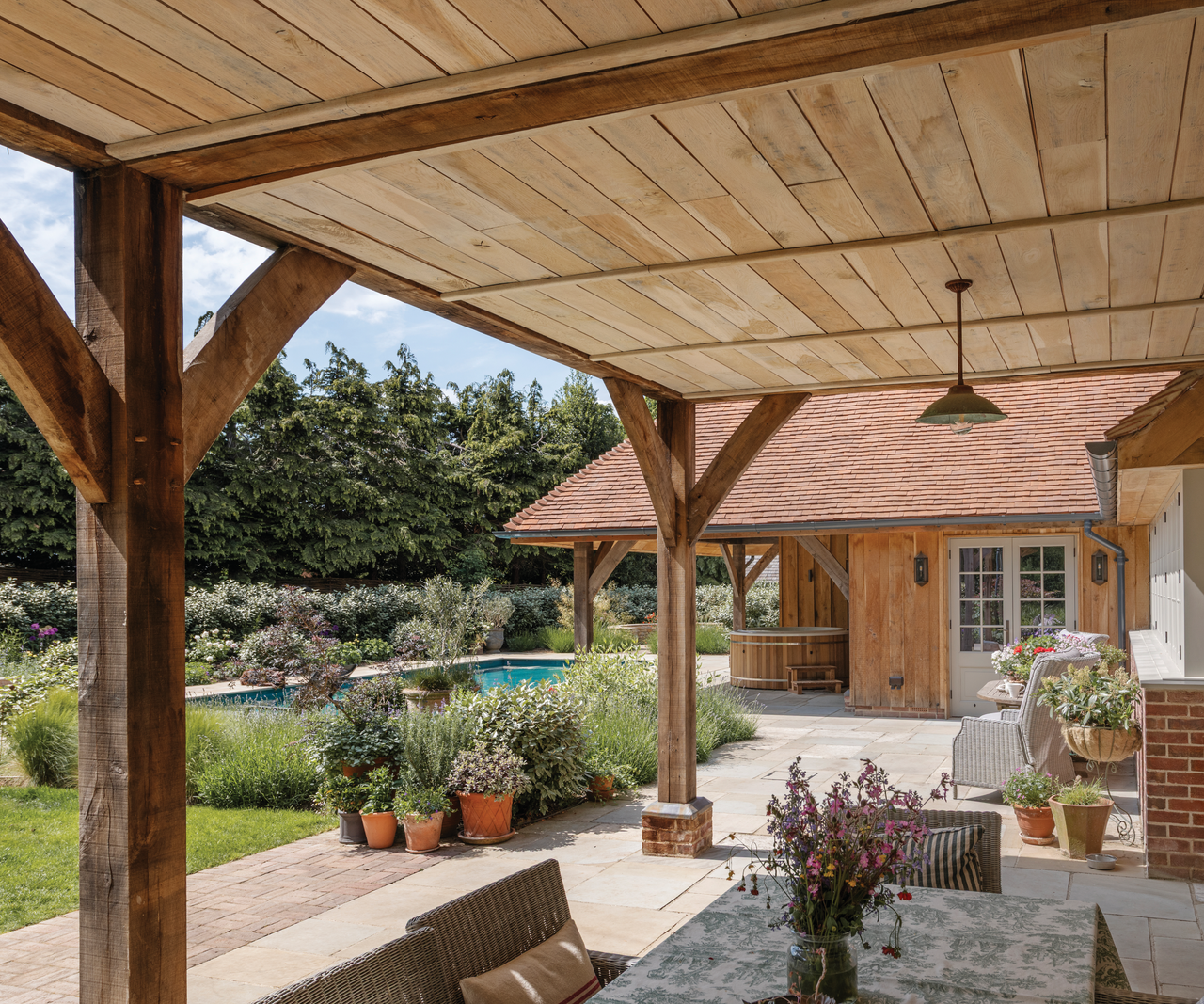 table underneath wooden pergola with pool in left far shot
