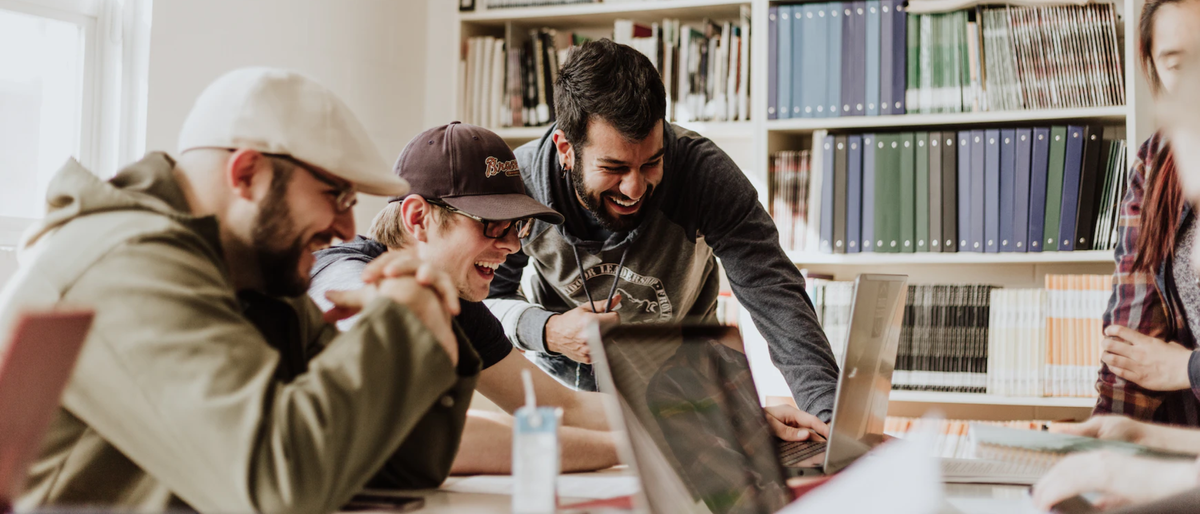 Three workers around a laptop laughing