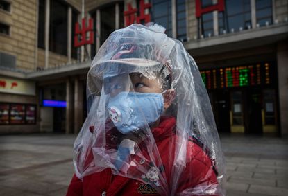 A boy in Beijing wears a mask and plastic over his face to protect him from getting sick.