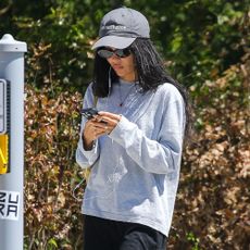 Zoe Kravitz walks down the street wearing an oversized t-shirt with wide-leg trousers and black ballet flats.