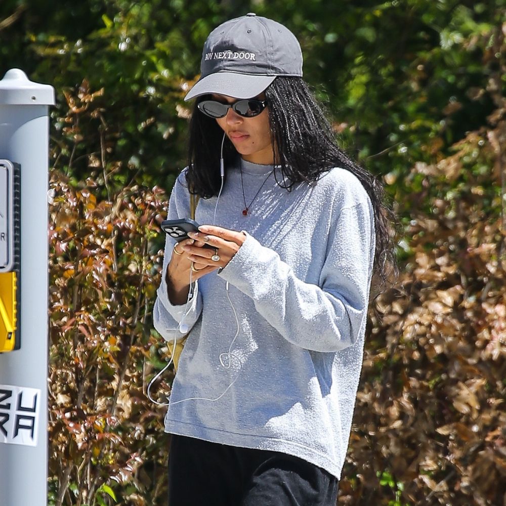 Zoe Kravitz walks down the street wearing an oversized t-shirt with wide-leg trousers and black ballet flats.