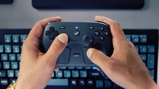 Hands holding Steam Controller above PC keyboard.