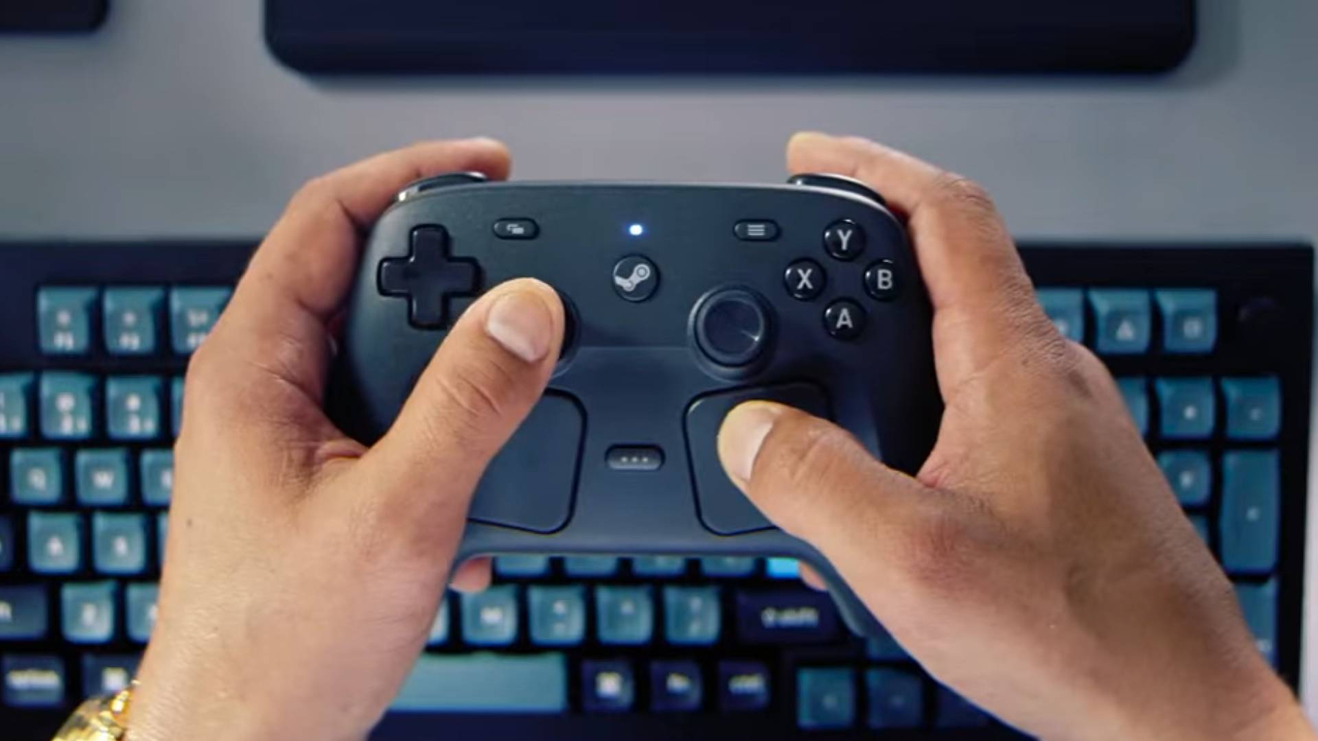 Hands holding Steam Controller above PC keyboard.