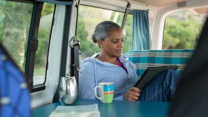 A woman works on her laptop while sitting in a camper van.