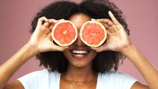 Woman holding grapefruit halves over her eyes