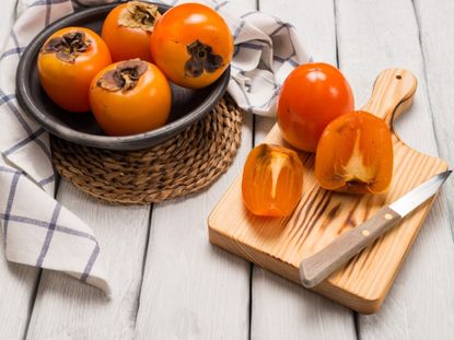 Persimmons in a basket and sliced persimmons on a cutting board
