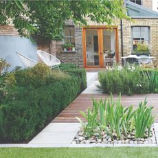 Garden decking and patio area surrounded by hedges and plants