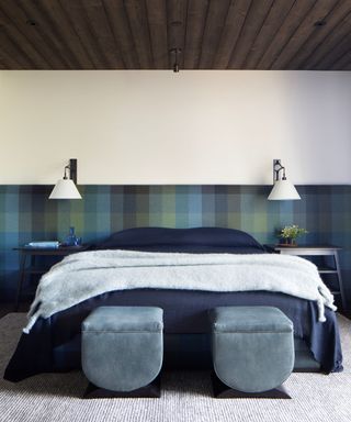 blue bedroom with wood ceiling and two ottomans at foot of bed