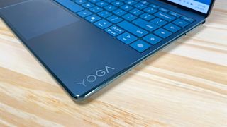 Close up of the glossy Yoga logo on the keyboard deck of the Lenovo Yoga Slim 9i