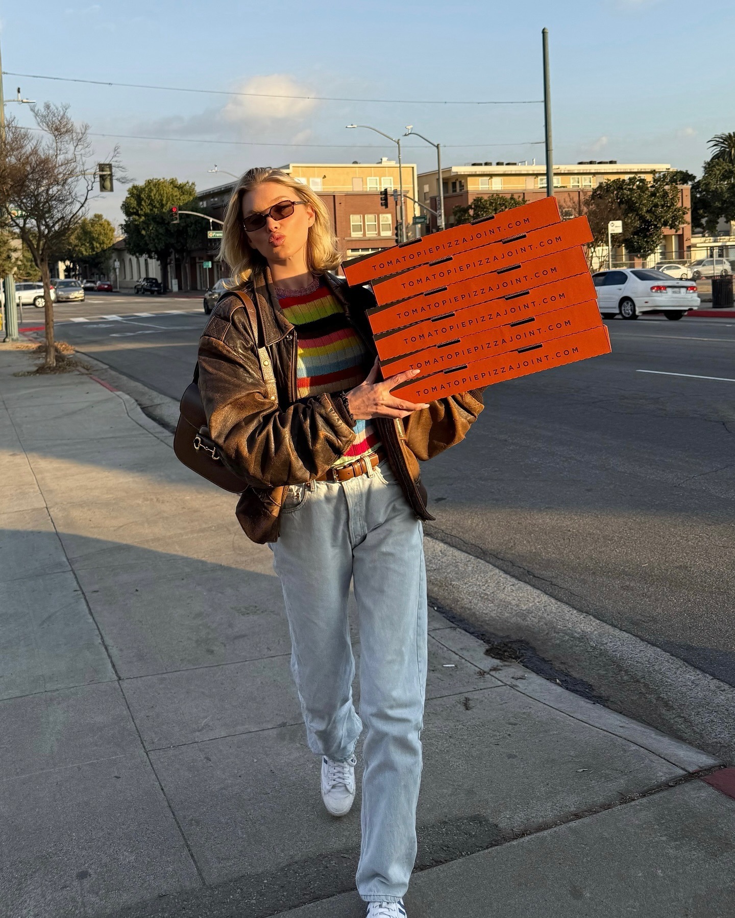 Elsa Hosk wearing a distressed leather jacket with jeans and a striped sweater.