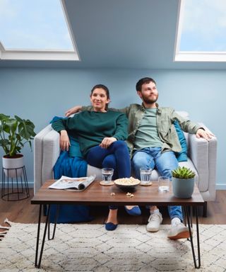 man and woman sat on sofa beneath skylights and walls and reveals painted blue