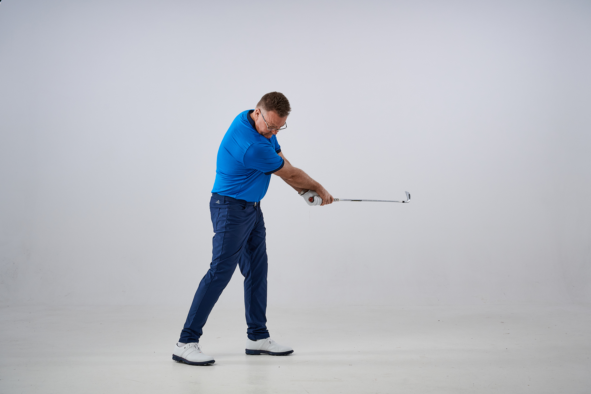 John Jacobs demonstrating the step-back drill to encourage the hands to follow a better path and release the golf club more effectively through impact