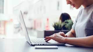 Une femme assise à une table, travaillant sur un ordinateur portable MacBook