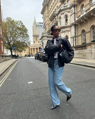 woman wearing black bomber jacket and baggy jeans with stiletto heels