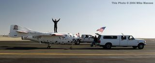 Pilot Mike Melvill has some fun celebrating his successful private suborbital flight atop SpaceShipOne, as the tow vehicle pulls it to the general viewing area.