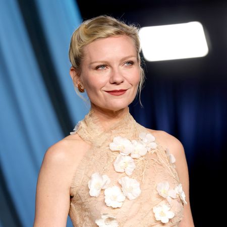 a white woman with blonde hair wearing a floral halter dress and posing in front of a blue background