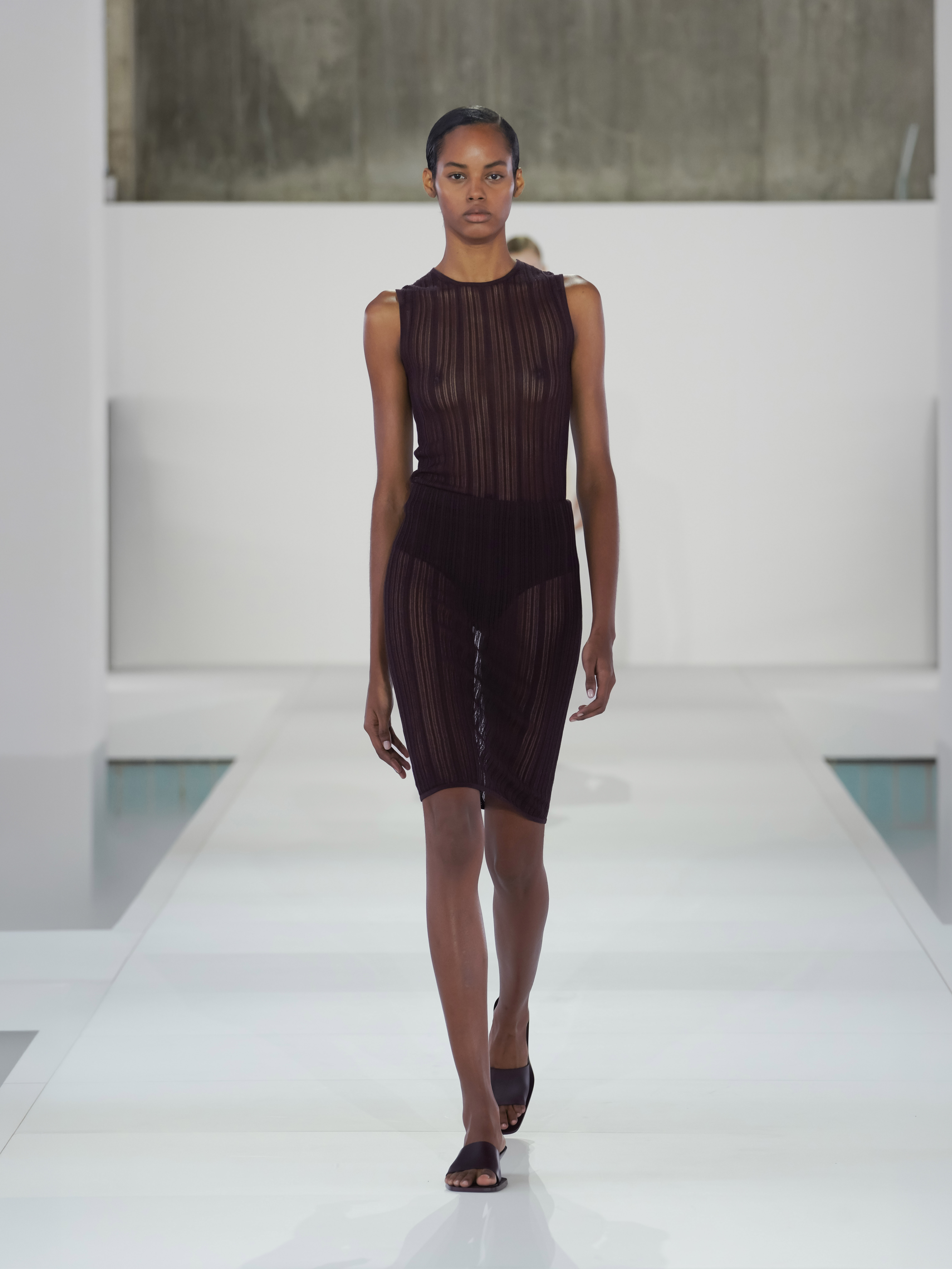 A model walking in the SS26 COS show in Seoul, South Korea, wearing a sheer burgundy midi dress.