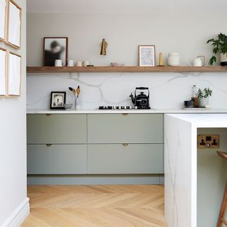 Simple open plan kitchen with marble splasback and long wooden shelf