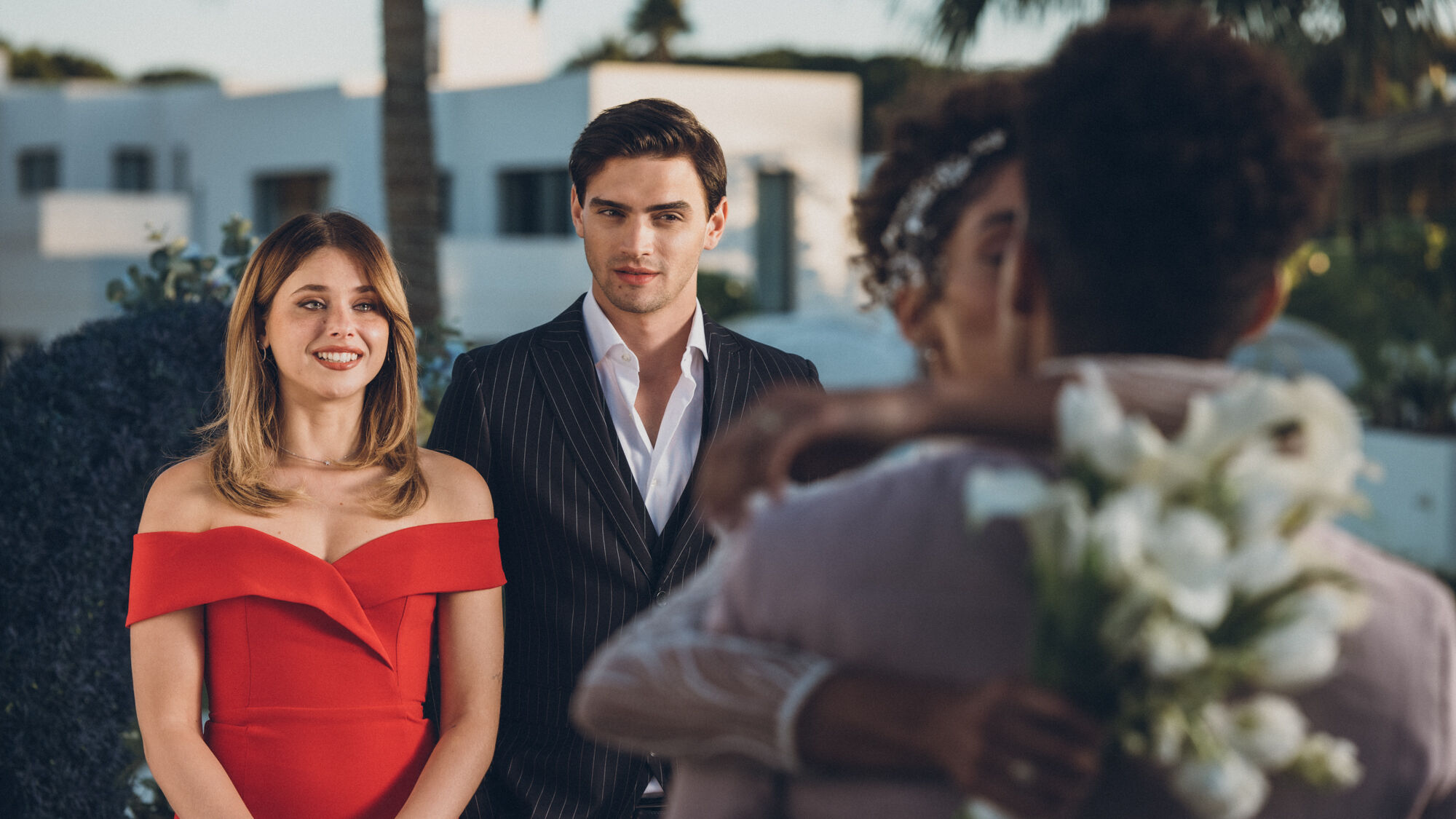 Noah and Nick smile at Jenna and Lion kissing on their wedding day.