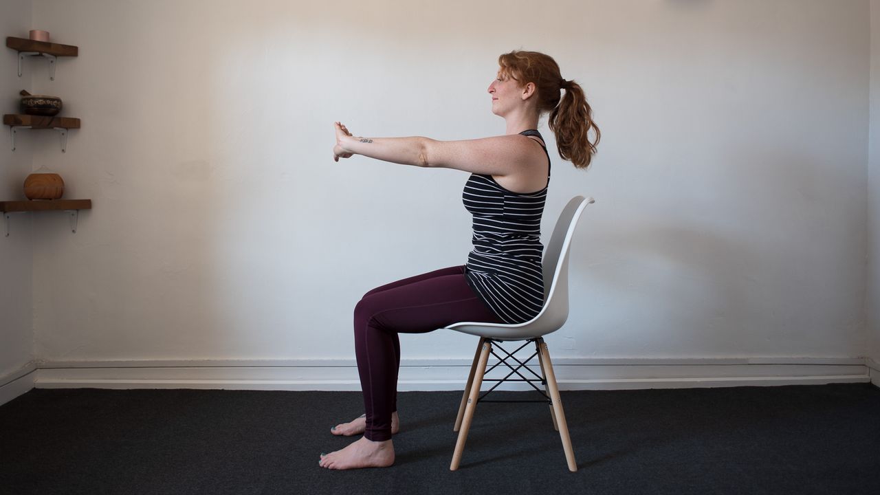 desk exercises: woman gripping one wrist and stretching her hands forwards