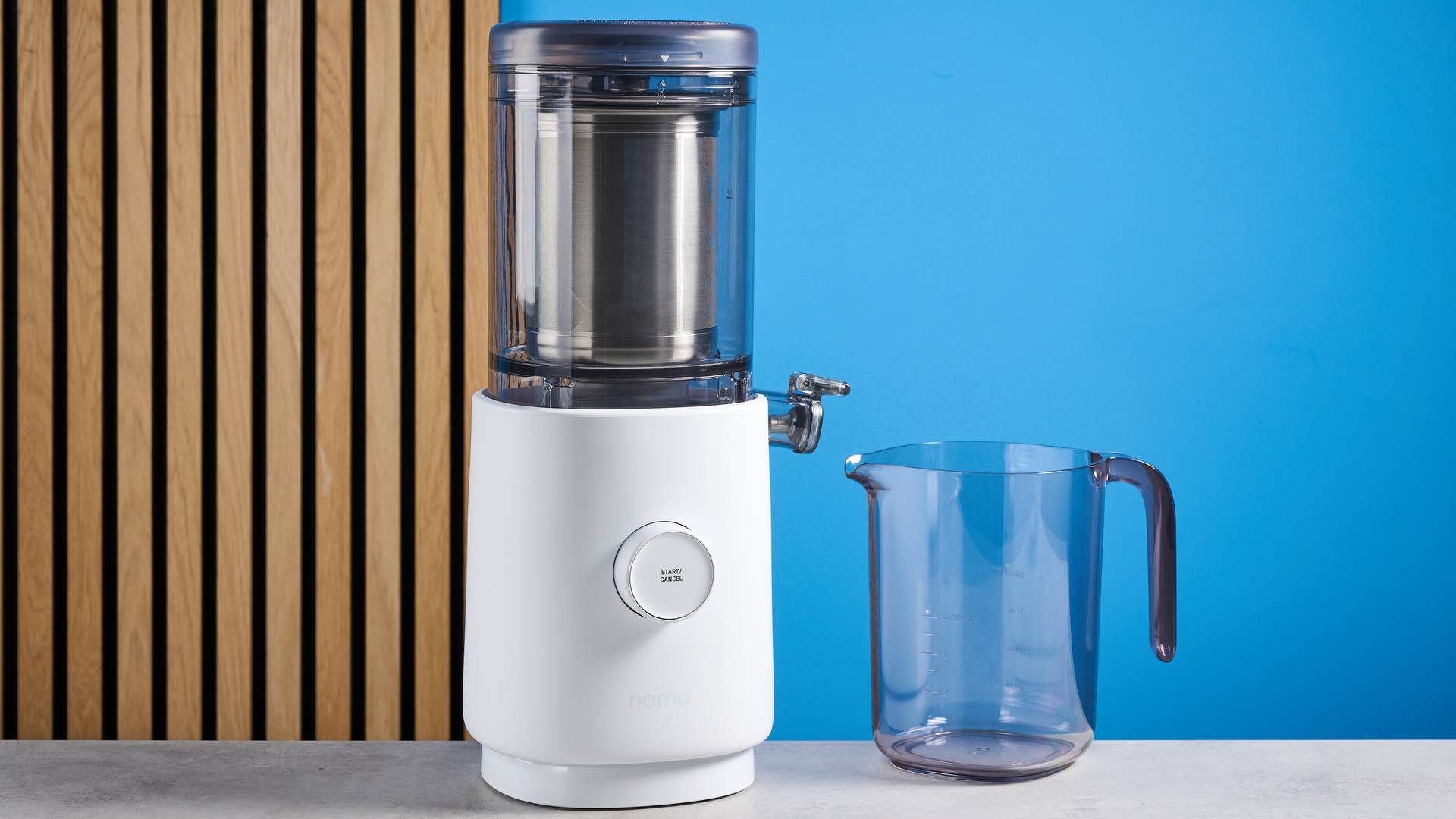 the nama m1 plant-based milk maker in white with a pitcher, blade frame, and strainer, and a pulp mat accessory with a brush