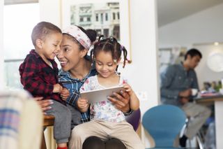 Mother, son and daughter having fun with tablet - stock photo