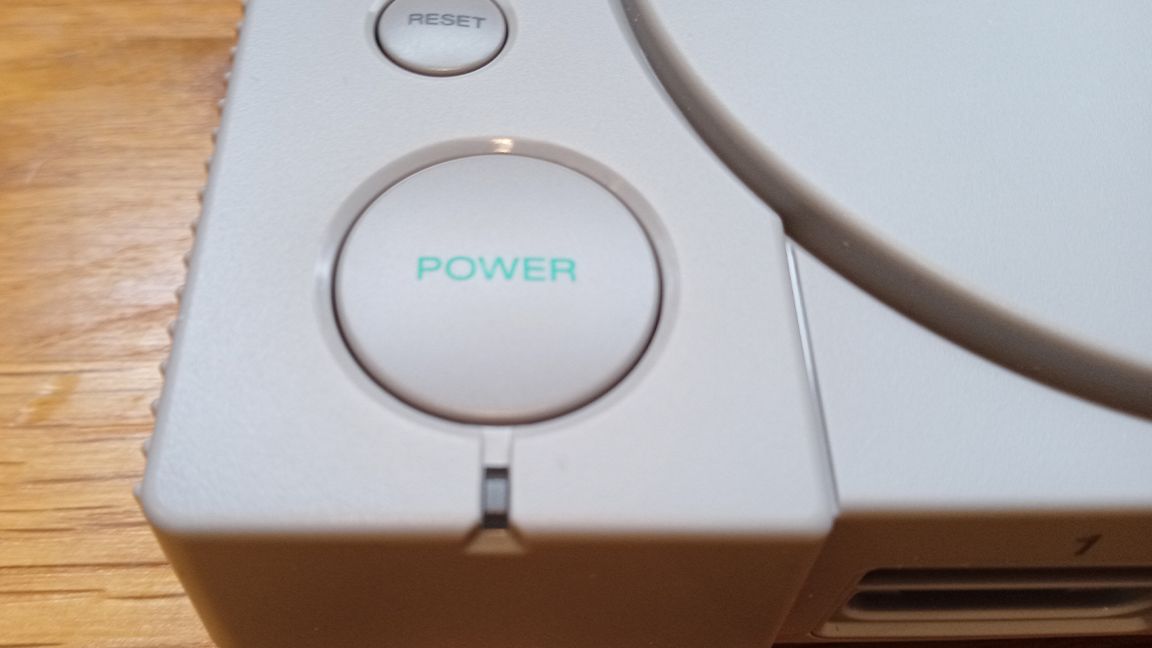A photo of the PlayStation Classic's power button on a wooden table