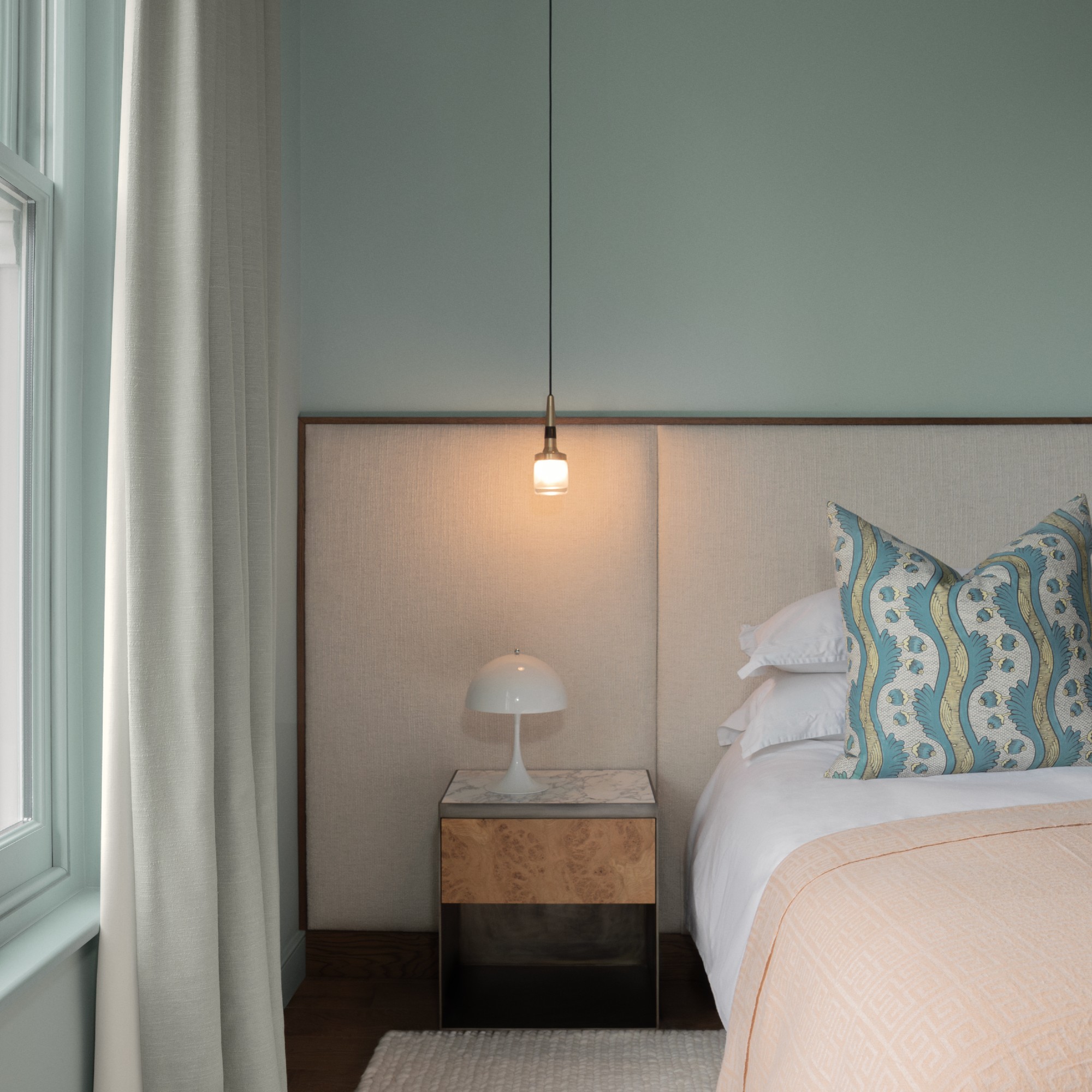 A bedroom painted in Lick&#039;s Blue 03 with a bed with a large upholstered headboard