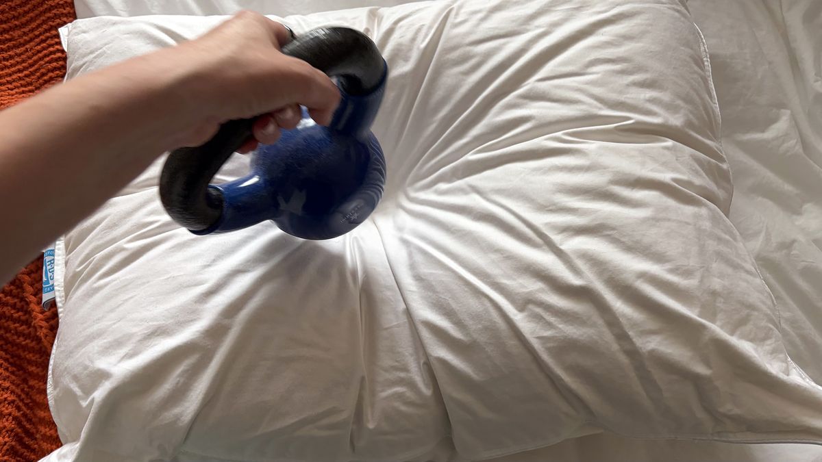 A hand removes a 10lb pillow from the Downright Mackenza WD pillow. The weight has left an indent in the surface