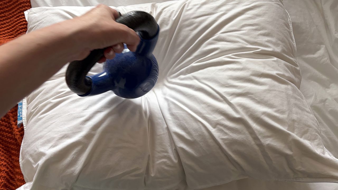A hand removes a 10lb pillow from the Downright Mackenza WD pillow. The weight has left an indent in the surface