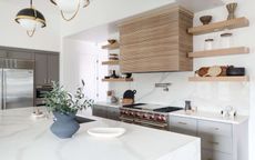 A kitchen with marble counters and wooden open shelving