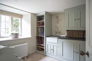 A large mudroom with a white radiator, wall storage and a sink