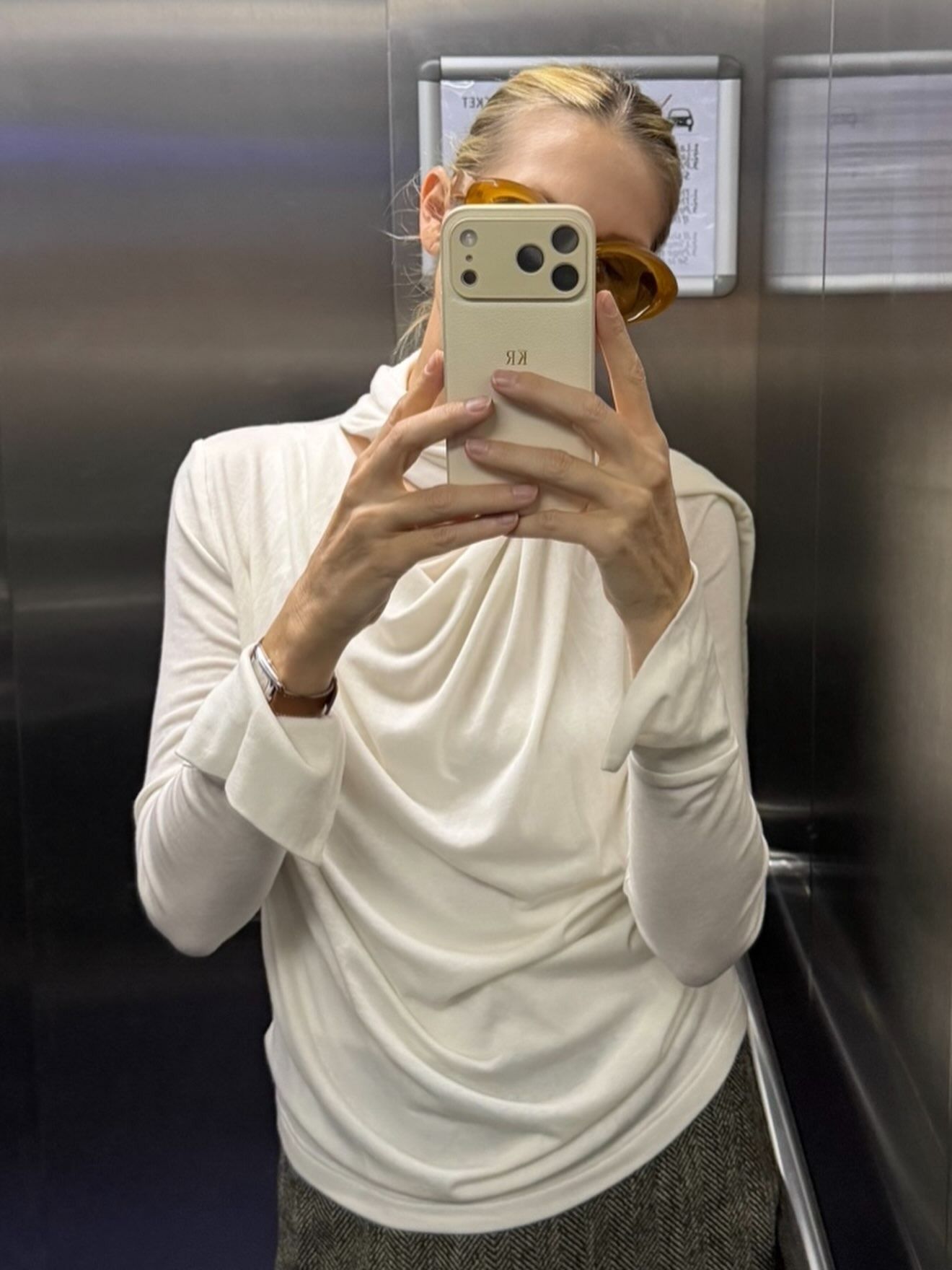Kelly Rutherford takes a mirror selfie wearing a draped fine-knit jumper with oversized sunglasses.