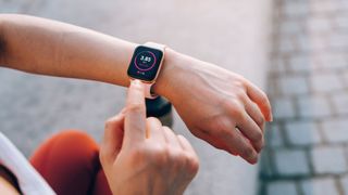 Woman looking down at her fitness tracker watch on her wrist, moving to tap the screen with 3.85km distance number on the screen