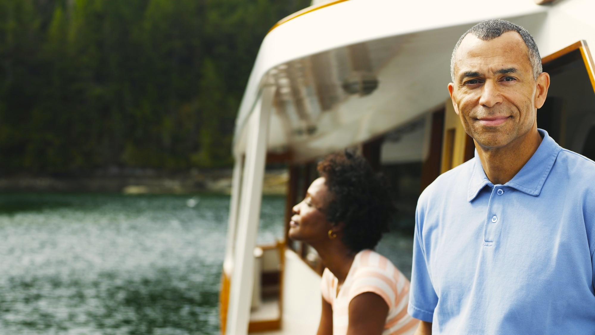An attractive man and woman in their 50s lounge on a yacht.