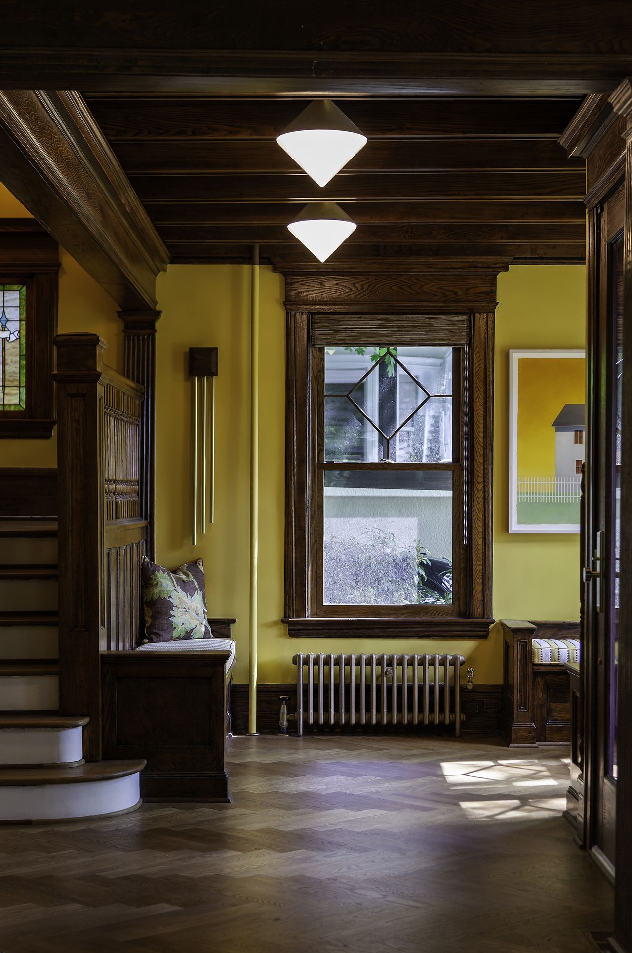 wood paneled entryway with yellow painted walls, herringbone floor, wooden bench, pendant lights