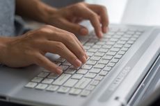 A person typing on a computer keyboard.