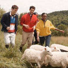 A group of people in a field with sheep wearing Nautica fields