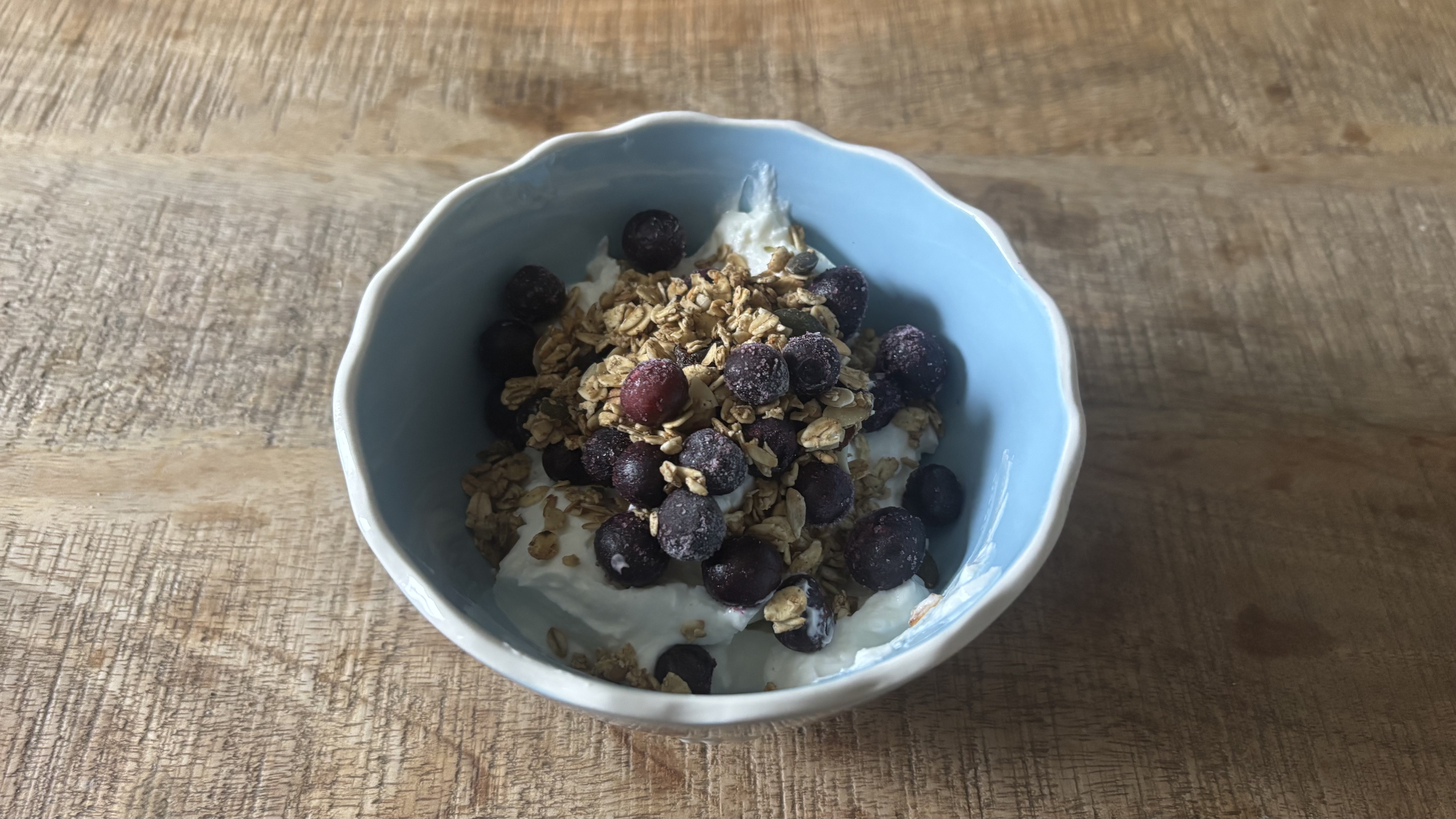 Blueberries and granola sprinkled on yogurt.