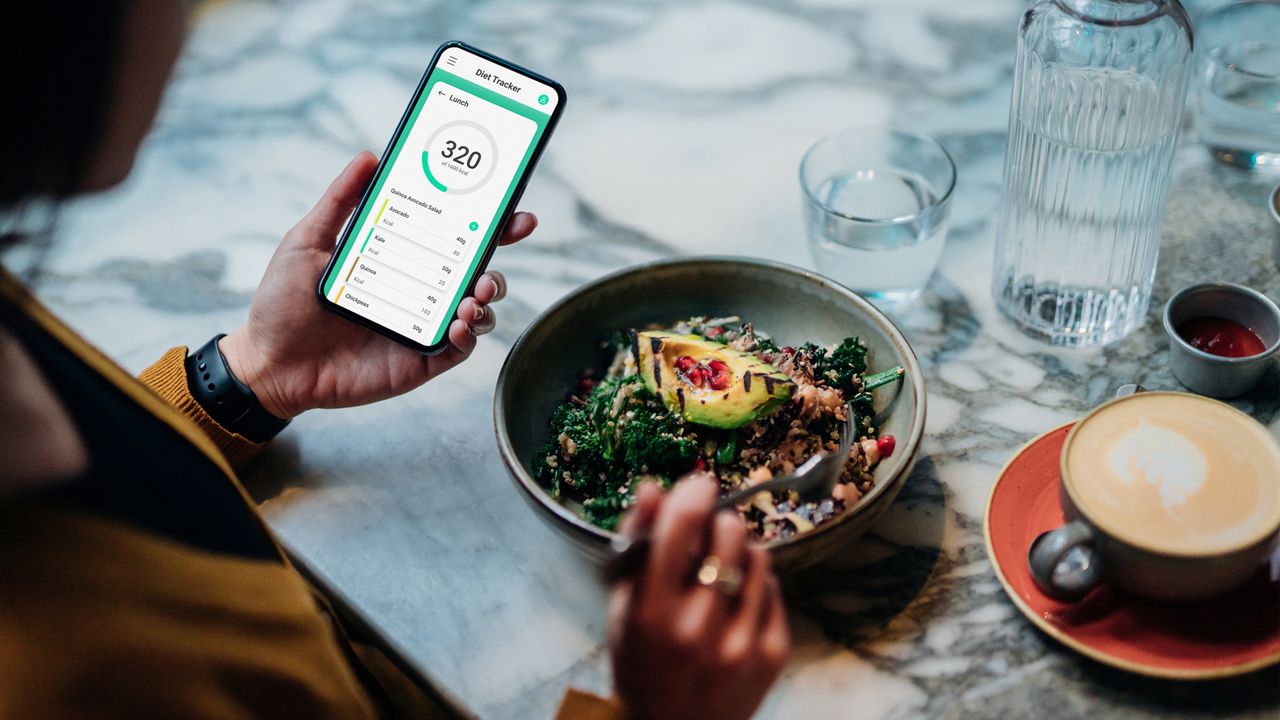 woman using a calorie counting app with her lunch