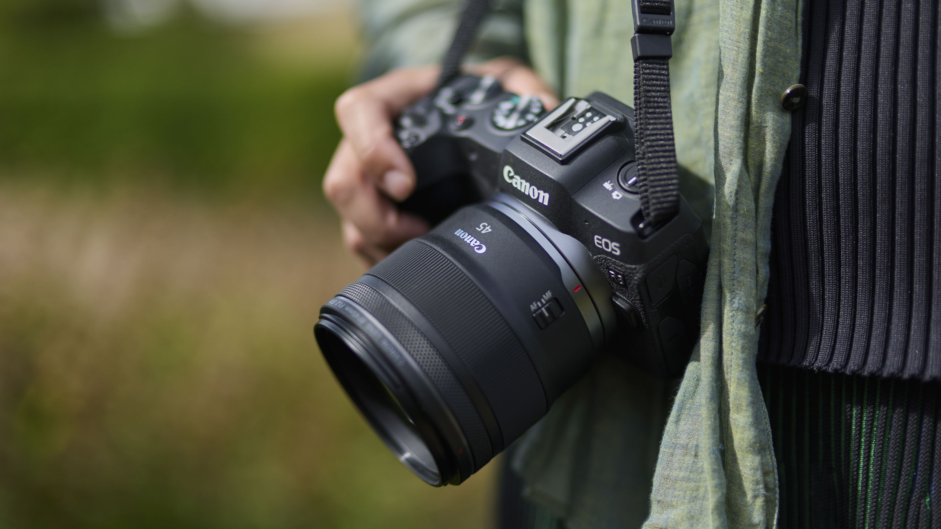 Canon RF 45mm F1.2 STM lens in the hand, attached to a Canon camera