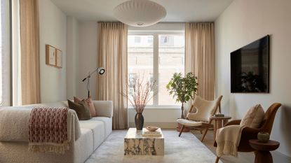 minimalist living room in neutral colors, boucle sofa, sheepskin chair, and velvet chair opposite