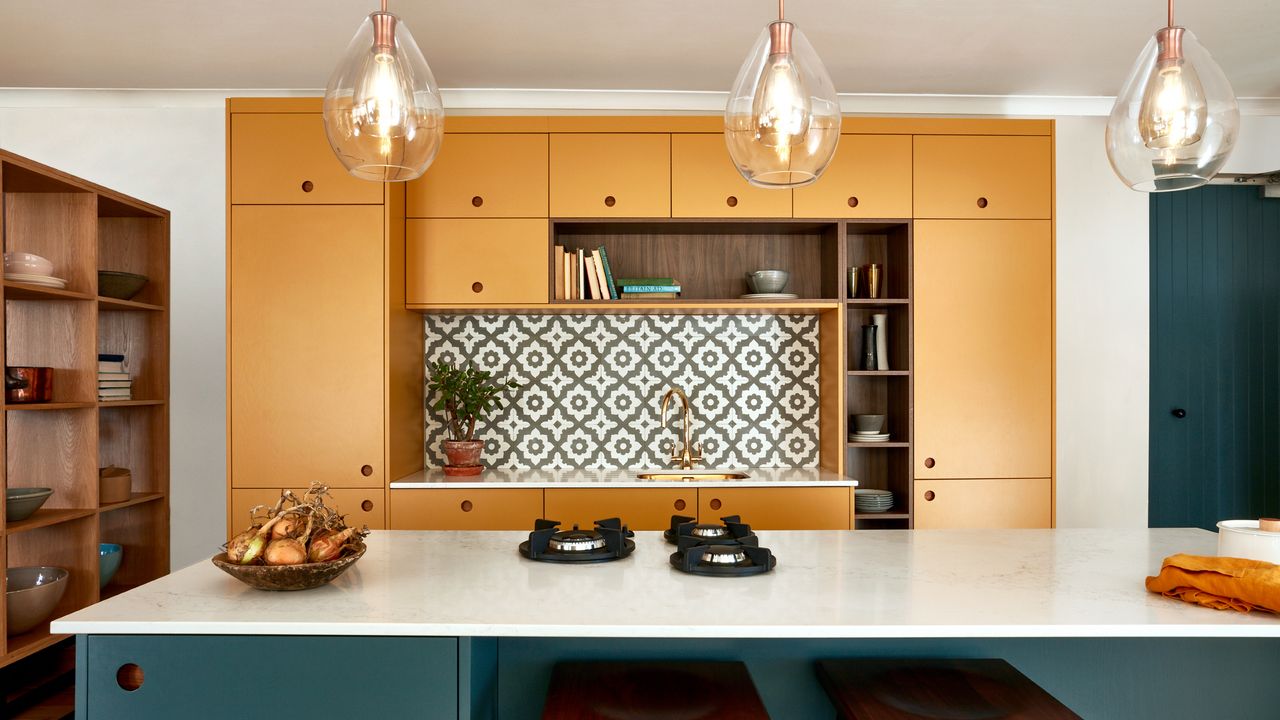 best colour combinations, teal and mustard kitchen with white marble topped island, tile splash back, mustard cabinetry, glass pendant lights