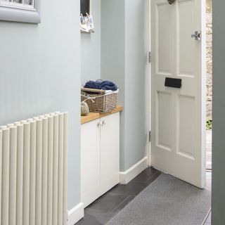 Light blue hallway with farmhouse white door and white built in storage unit.