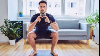 Man doing one of the best ab exercises, a goblet squat, with a kettlebell