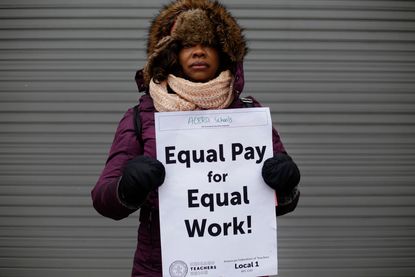 A Chicago teacher holds a sign demanding equal pay.