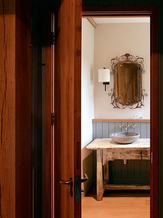 View through dark wooden door of sink and mirror