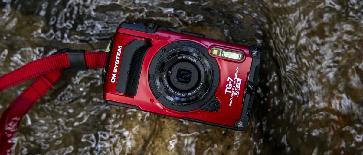 The OM System Tough TG-7 camera lying in a stream