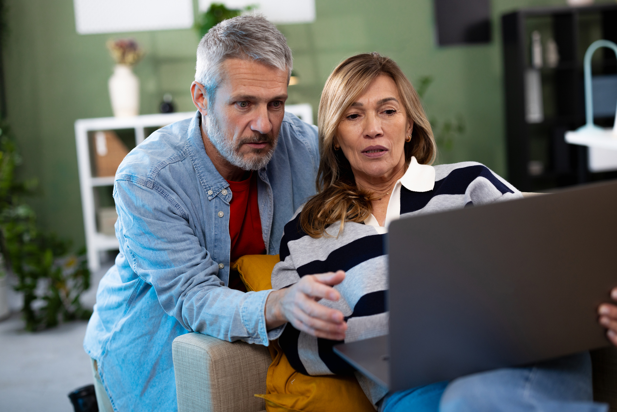 Portrait of a happy mature couple relaxing at home and using a laptop together