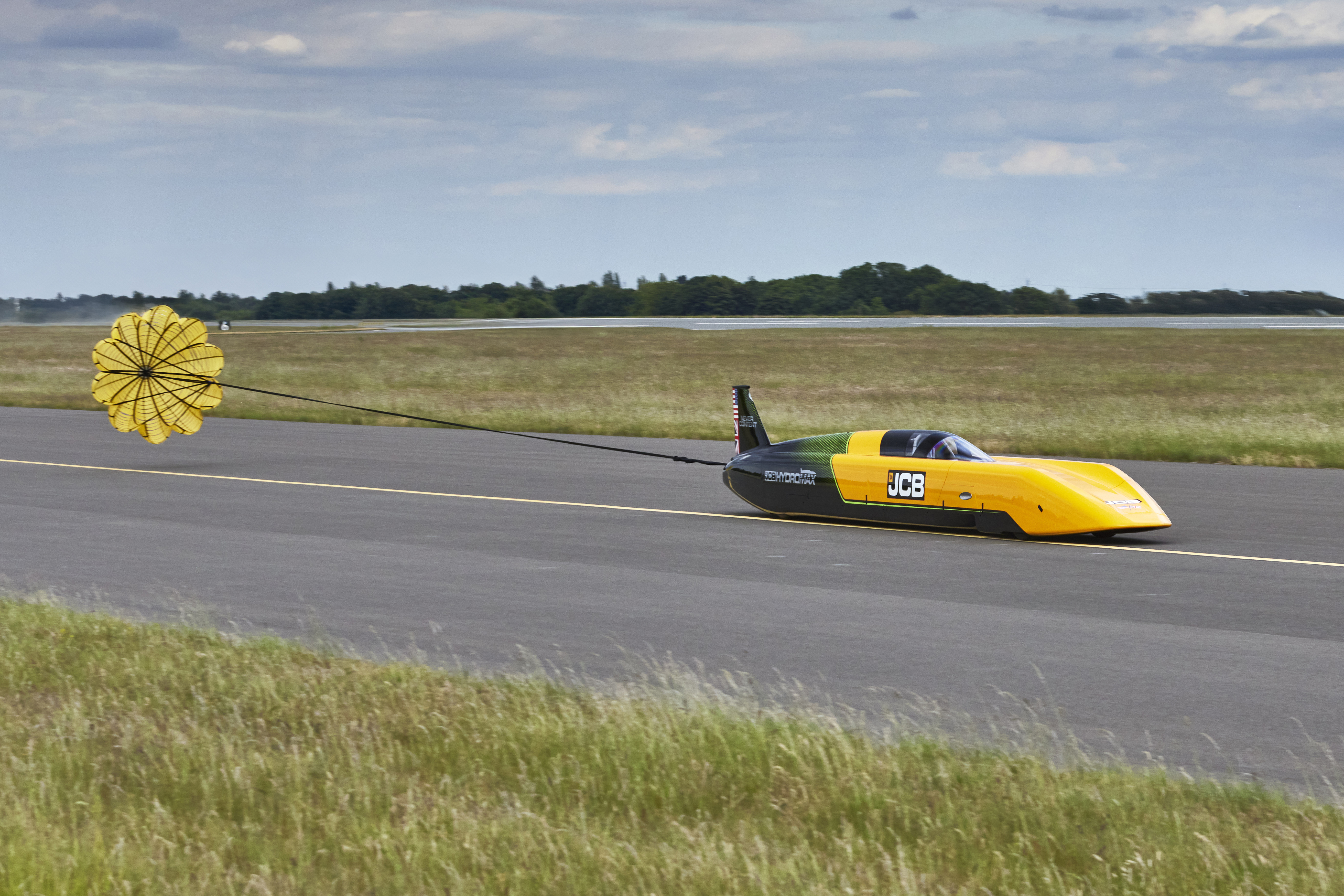 The JCB Hydromax tears down the runway, with its parachute deployed.